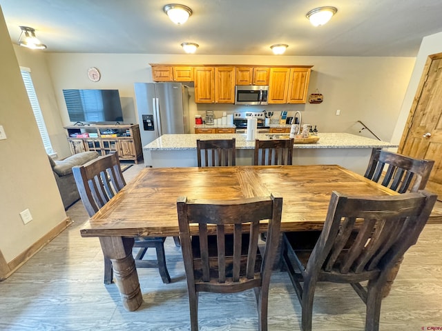 dining area with baseboards and light wood finished floors