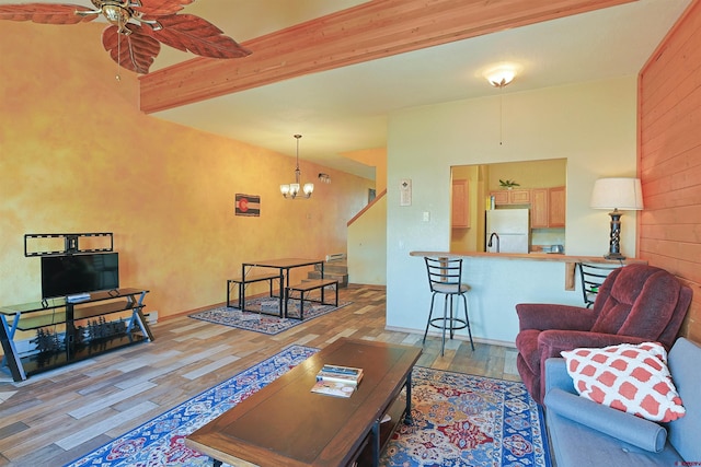 living room featuring ceiling fan with notable chandelier, beamed ceiling, and wood finished floors