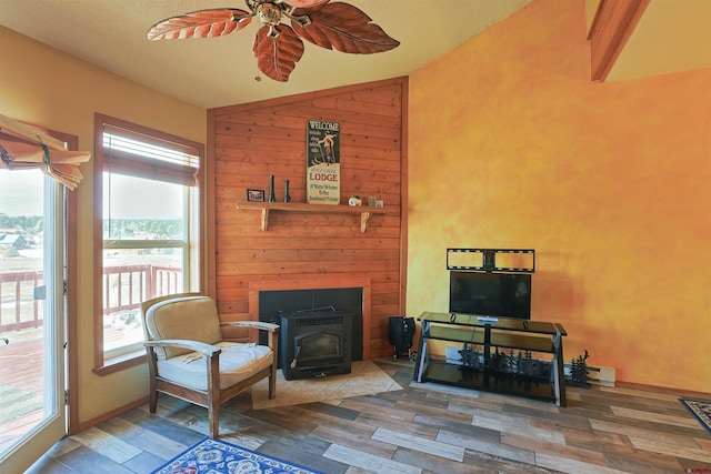 sitting room with vaulted ceiling, ceiling fan, wood finished floors, and a wood stove