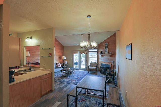 interior space featuring a textured wall, lofted ceiling, dark wood-type flooring, a textured ceiling, and a sink