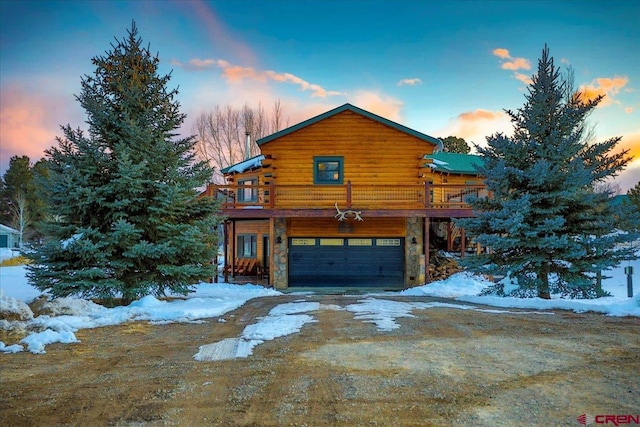 view of snowy exterior featuring log exterior, stone siding, an attached garage, and driveway