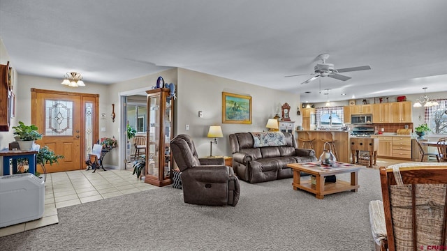 living room featuring light tile patterned floors, ceiling fan with notable chandelier, and light colored carpet