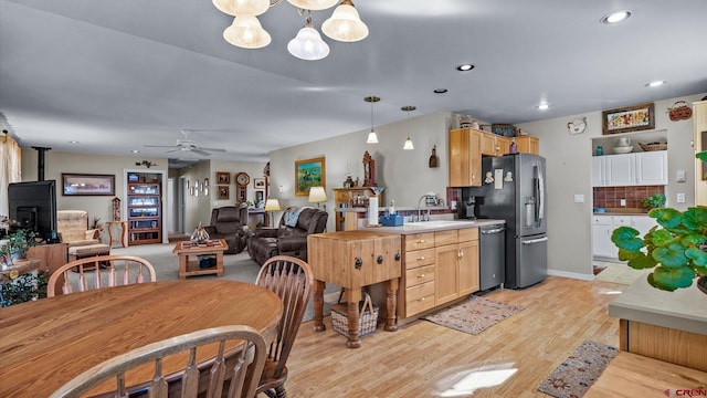 kitchen with decorative backsplash, appliances with stainless steel finishes, a wood stove, light wood-style floors, and a sink