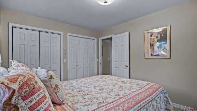 bedroom with two closets and baseboards