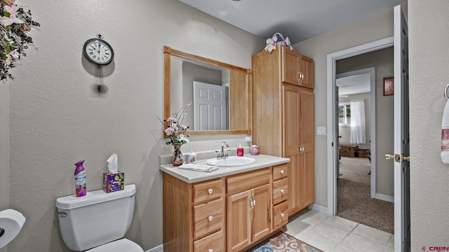 half bathroom with tile patterned flooring, vanity, toilet, and baseboards