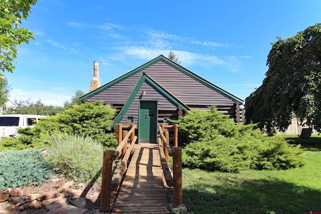 view of front of home with a chimney and log siding