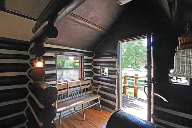 interior space featuring rustic walls, vaulted ceiling, and wood finished floors