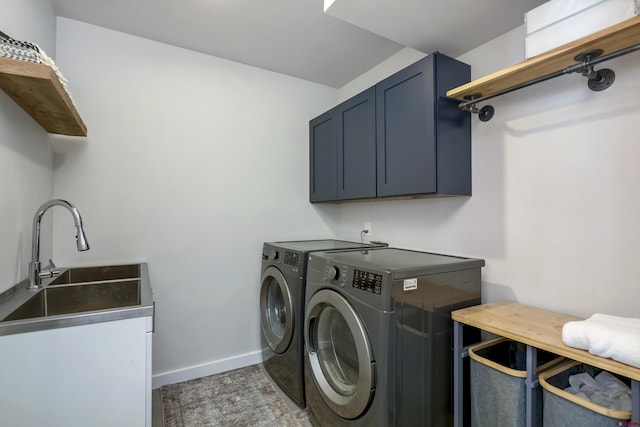 clothes washing area with cabinet space, baseboards, washer and clothes dryer, and a sink