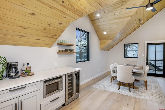 dining area with beverage cooler, baseboards, a ceiling fan, wooden ceiling, and light wood-style flooring