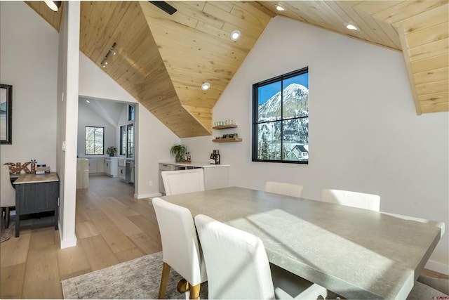 dining area with light wood-style floors, wooden ceiling, a healthy amount of sunlight, and high vaulted ceiling