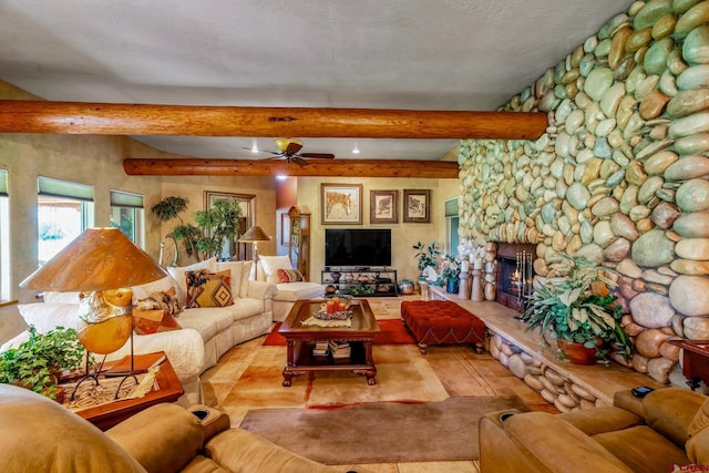 living area featuring a textured ceiling, beamed ceiling, a fireplace, and a ceiling fan