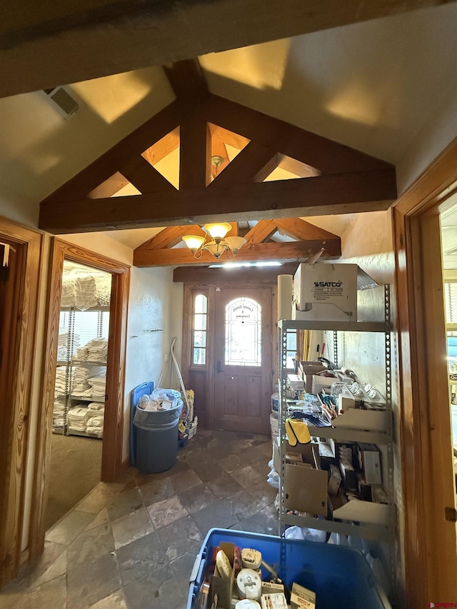 entrance foyer featuring lofted ceiling, stone tile floors, and visible vents