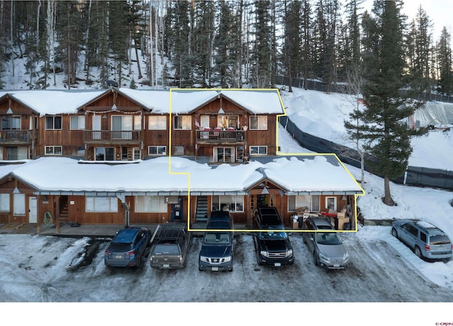 snow covered house featuring a balcony