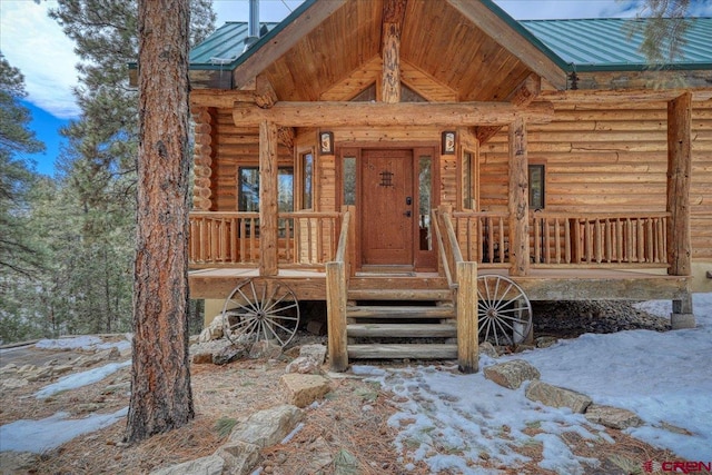 property entrance featuring a porch, metal roof, and log siding