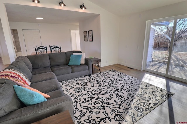 living area with lofted ceiling, light wood-type flooring, visible vents, and baseboards