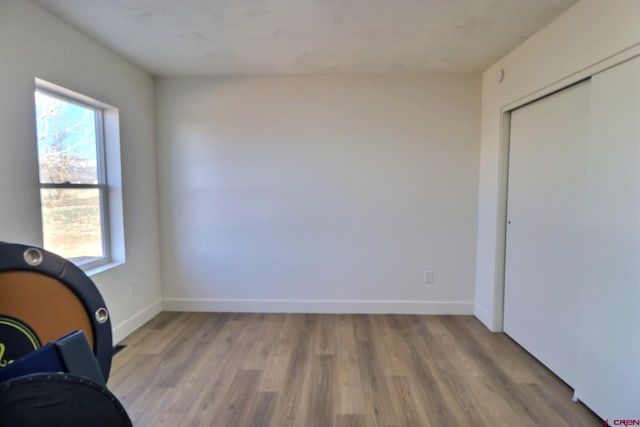 unfurnished bedroom with light wood-style floors, baseboards, and a closet