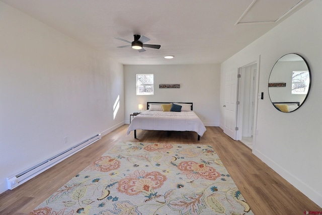 bedroom with light wood finished floors, baseboards, baseboard heating, and a ceiling fan