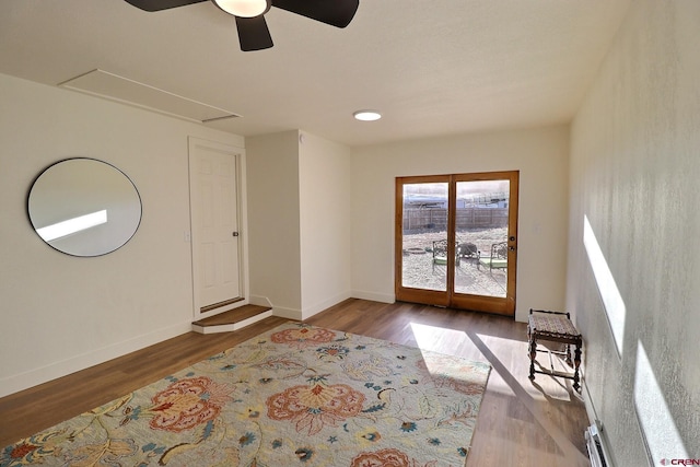 interior space with ceiling fan, wood finished floors, attic access, and baseboards