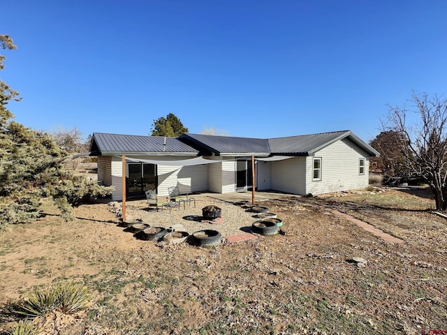 back of house featuring a fire pit, metal roof, and a patio