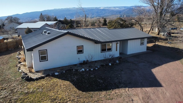 rear view of house with metal roof, fence, and a mountain view