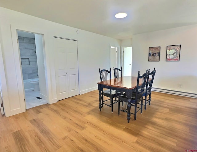 dining area featuring baseboard heating, light wood-style flooring, and baseboards