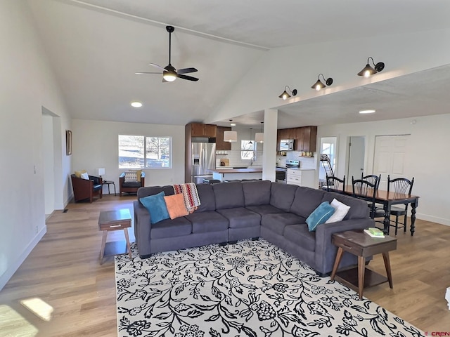 living area featuring ceiling fan, high vaulted ceiling, light wood-type flooring, and baseboards