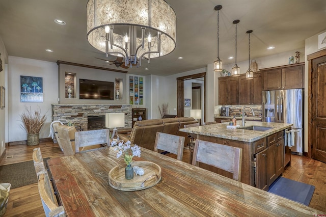 dining space with a notable chandelier, recessed lighting, wood finished floors, and a stone fireplace