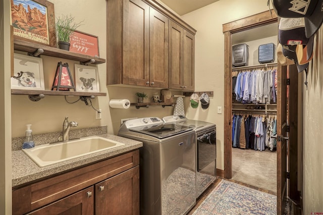 clothes washing area featuring independent washer and dryer, cabinet space, and a sink