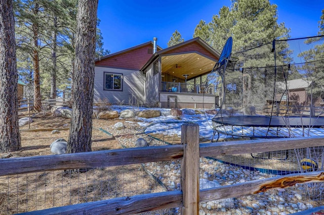 back of house featuring a trampoline and fence