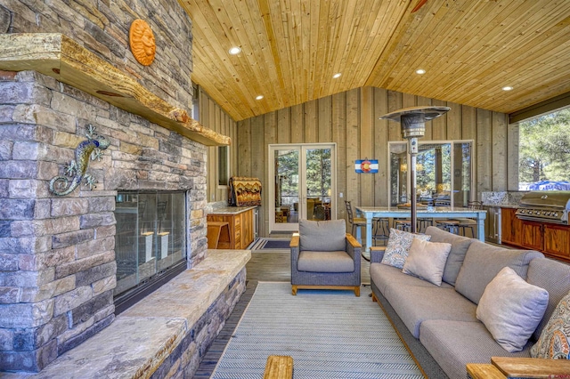 unfurnished living room with high vaulted ceiling, wood ceiling, an outdoor stone fireplace, and wood finished floors