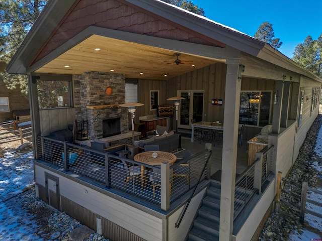 deck with ceiling fan, fence, an outdoor living space with a fireplace, and a patio