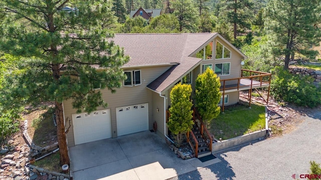 view of front of home with a garage, concrete driveway, and roof with shingles