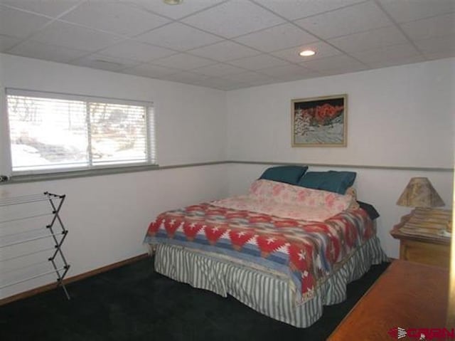 carpeted bedroom featuring a drop ceiling
