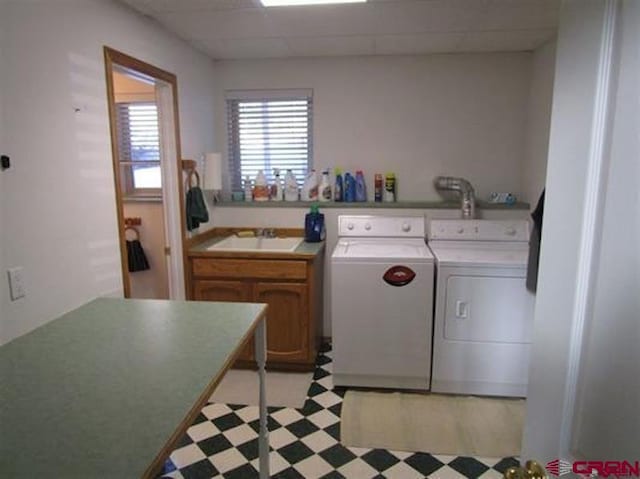 washroom with light floors, separate washer and dryer, a sink, and cabinet space