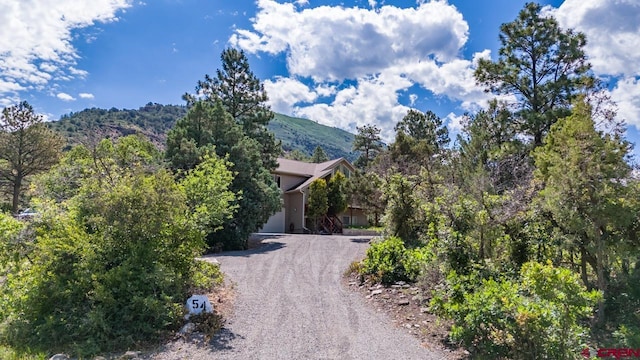 exterior space with a garage, gravel driveway, and a mountain view