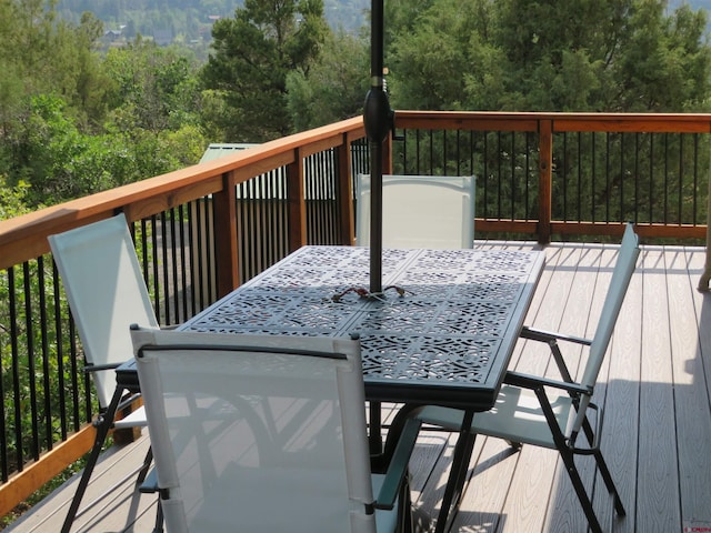 deck featuring outdoor dining area and a wooded view