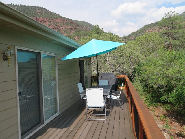 wooden deck with outdoor dining area, a grill, and a mountain view