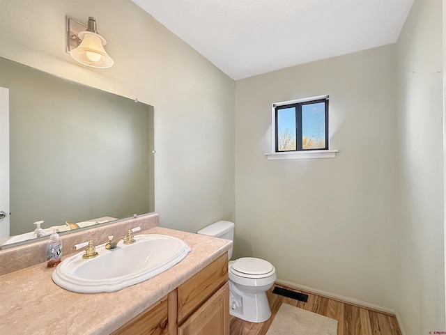 bathroom featuring visible vents, toilet, vanity, wood finished floors, and baseboards