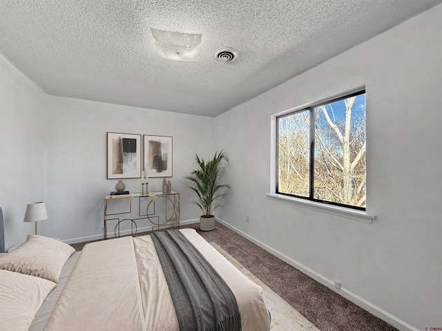 bedroom featuring baseboards, a textured ceiling, visible vents, and carpet flooring