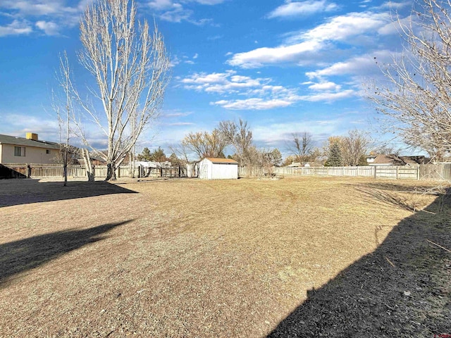 view of yard with a storage shed, a fenced backyard, and an outbuilding