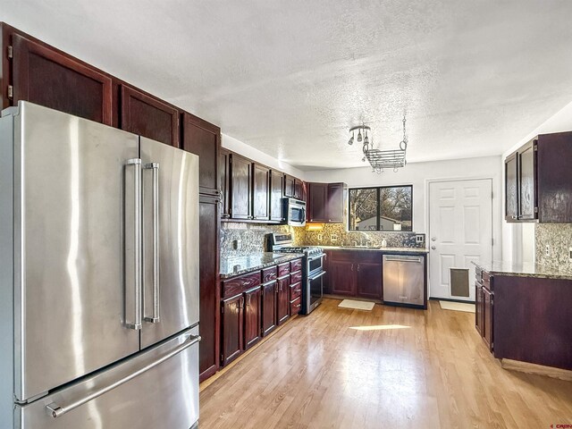 600 Willow Wood Ln, Delta, CO 81416 - kitchen featuring light wood-style flooring, a textured ceiling, backsplash, stainless steel appliances, and dark stone counters