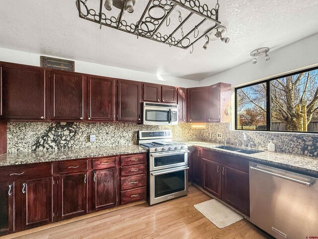 600 Willow Wood Ln, Delta, CO 81416 - kitchen featuring a sink, tasteful backsplash, stainless steel appliances, reddish brown cabinets, and light wood-style floors