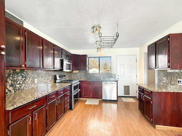 kitchen with stainless steel appliances, a sink, light wood finished floors, and dark brown cabinets