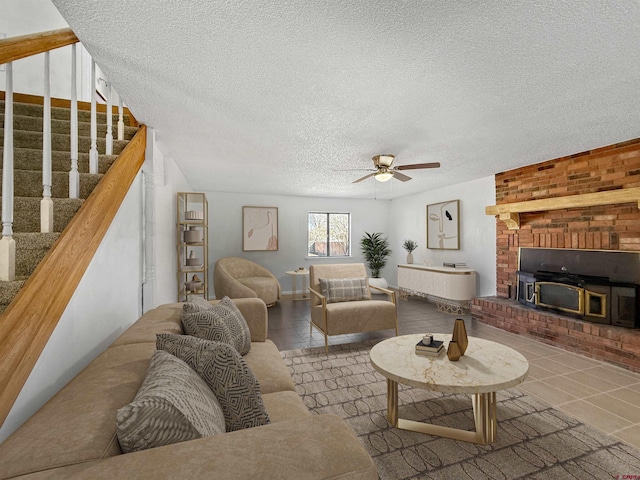 tiled living room with a fireplace, stairway, a textured ceiling, and ceiling fan