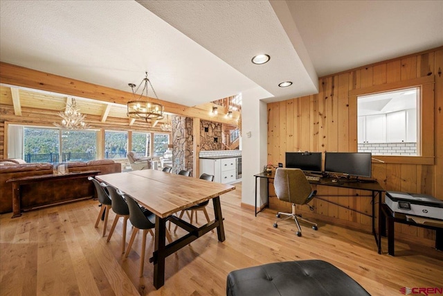 dining area with wood walls, a notable chandelier, light wood-style flooring, and beam ceiling