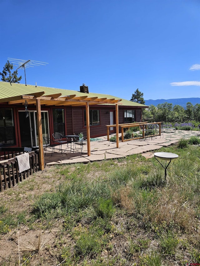 rear view of house with a chimney and a patio