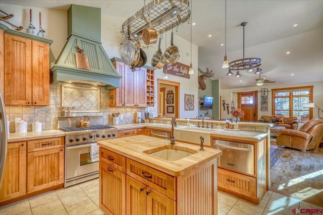 kitchen featuring a sink, an island with sink, butcher block countertops, high end stove, and a peninsula