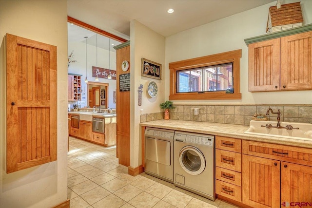 kitchen with a sink, light countertops, light tile patterned flooring, and washing machine and dryer