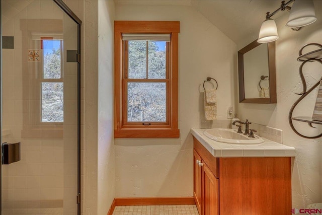 bathroom with lofted ceiling, a stall shower, baseboards, and vanity