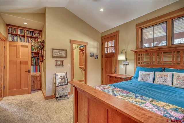 bedroom with lofted ceiling, baseboards, a walk in closet, and light colored carpet